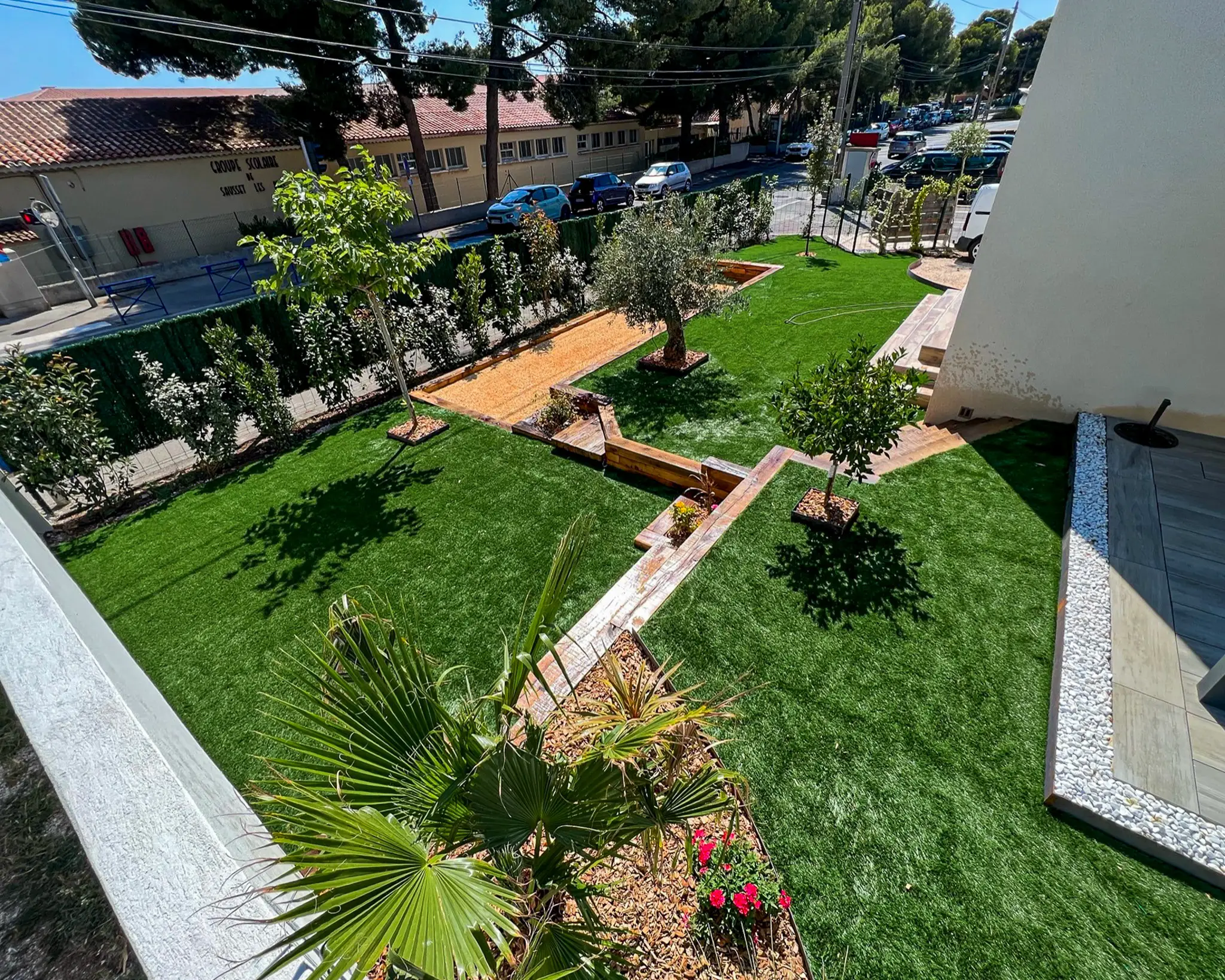 Aménagement paysager complet à Fuveau : gazon synthétique, soutènement et escaliers en poutres de chêne, jardinières et espace de convivialité.