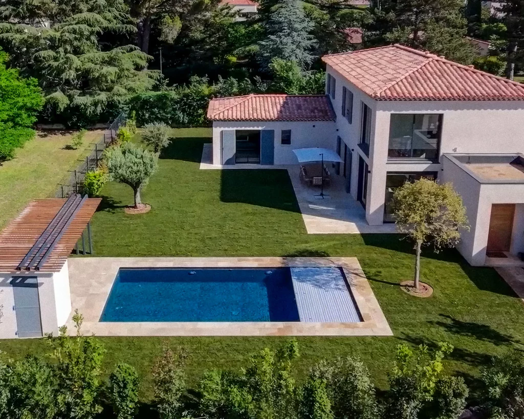 Vue aérienne d'un aménagement paysager complet à Aix-en-Provence : piscine, gazon en plaque méditerranéen, pergola sur mesure, terrasses en travertin et massifs provençaux.