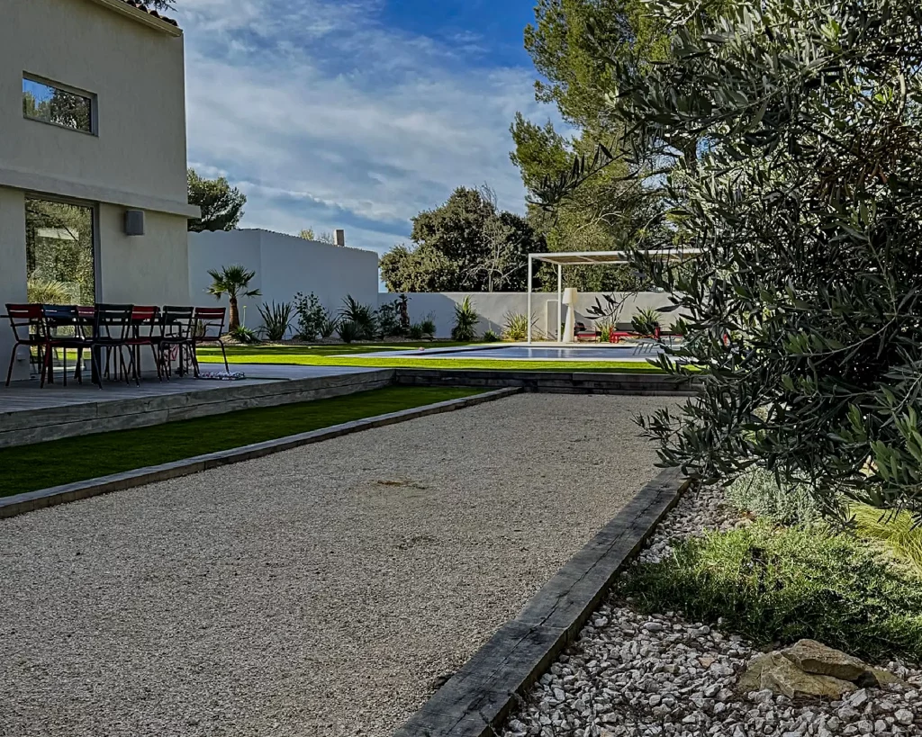 Aménagement de jardin complet à Bouc-Bel-Air : terrain de pétanque avec délimitation en bois, gazon synthétique, piscine et massif exotique/provençal