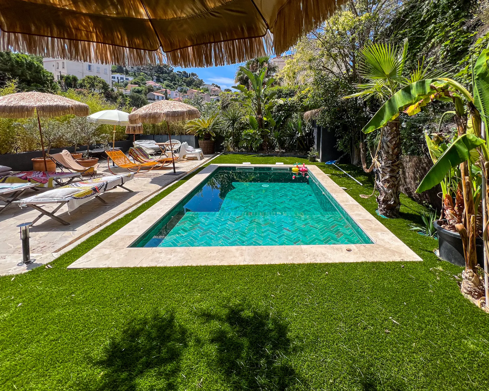 Installation de gazon synthétique de qualité autour d'une piscine avec plage carrelée, créant un espace de détente vert et sans entretien à Marseille.