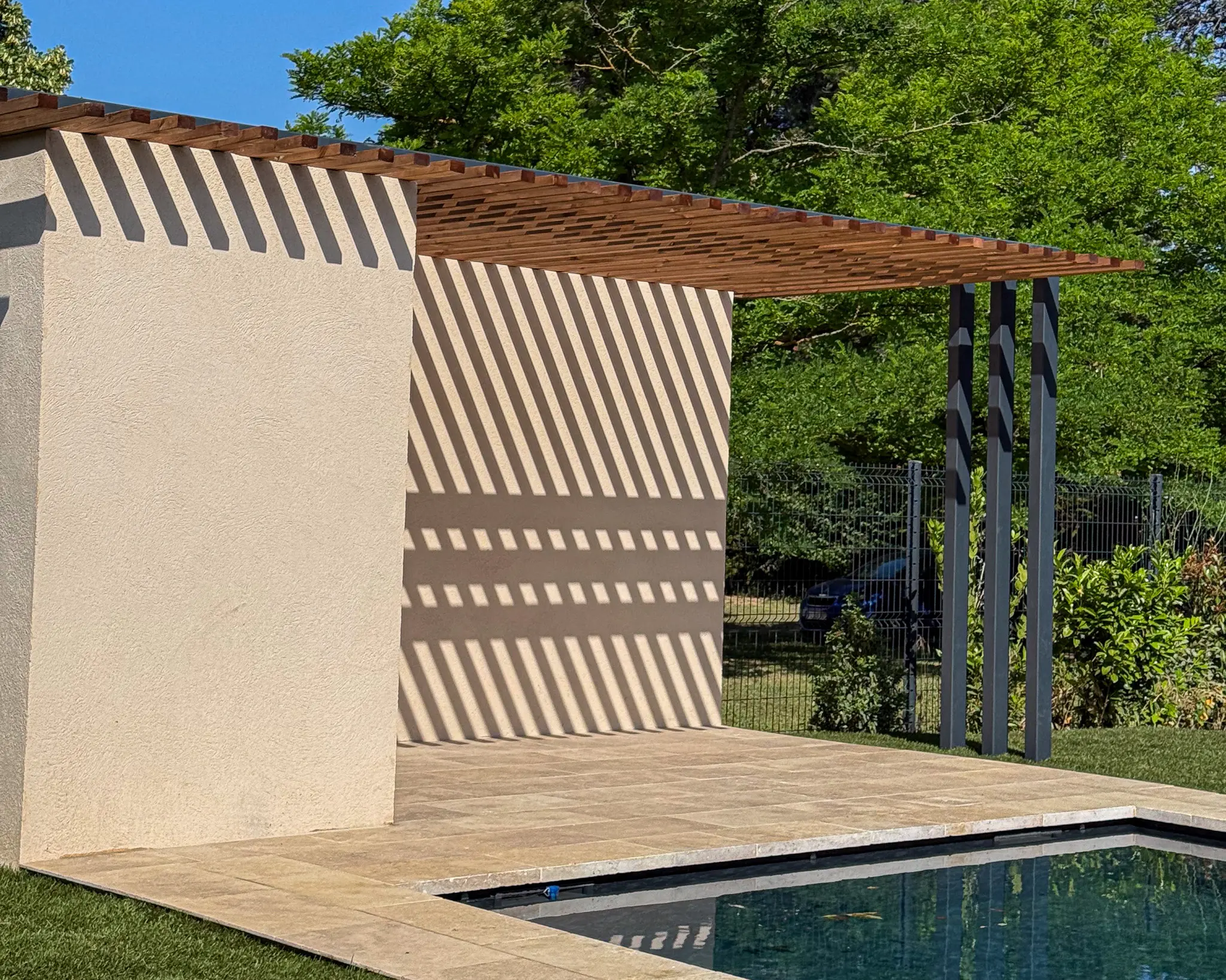Pergola moderne et design sur mesure, en fer forgé thermolaqué noir avec un habillage en poutres de pin, installée près d'une piscine à Aix-en-Provence.