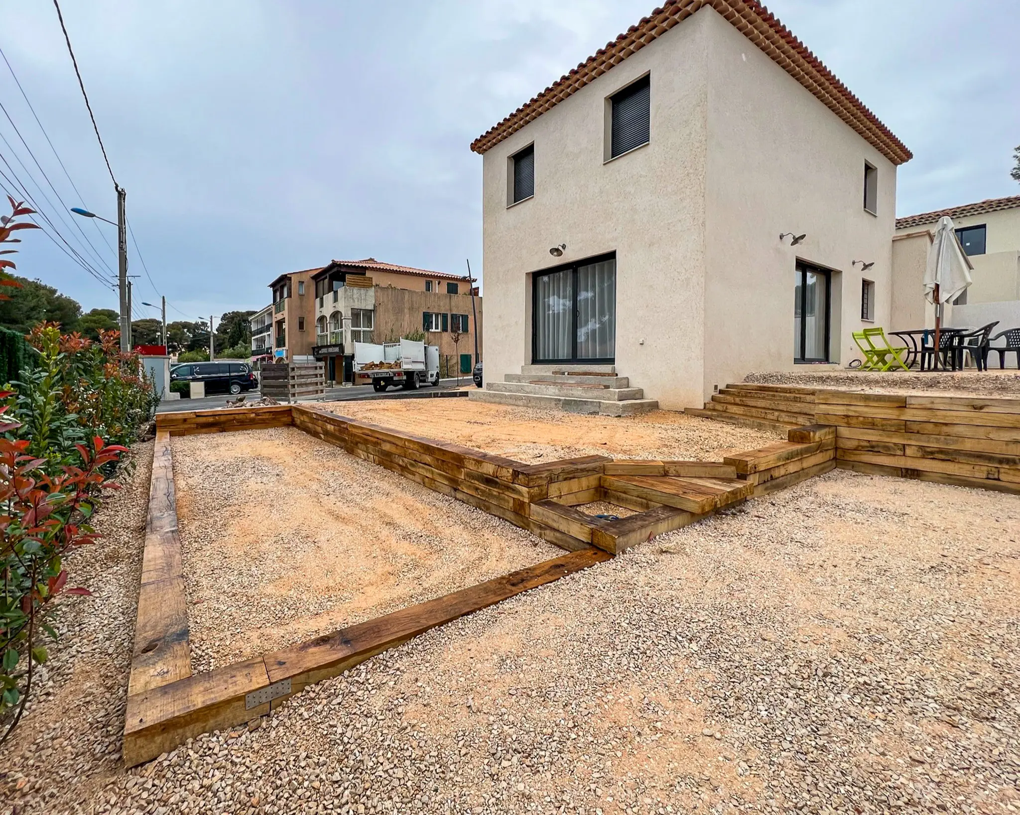 Phase de construction d'un terrain de pétanque avec bordures et marches en bois de traverse (traverses paysagères), lors d'un aménagement de jardin à Aix-en-Provence.